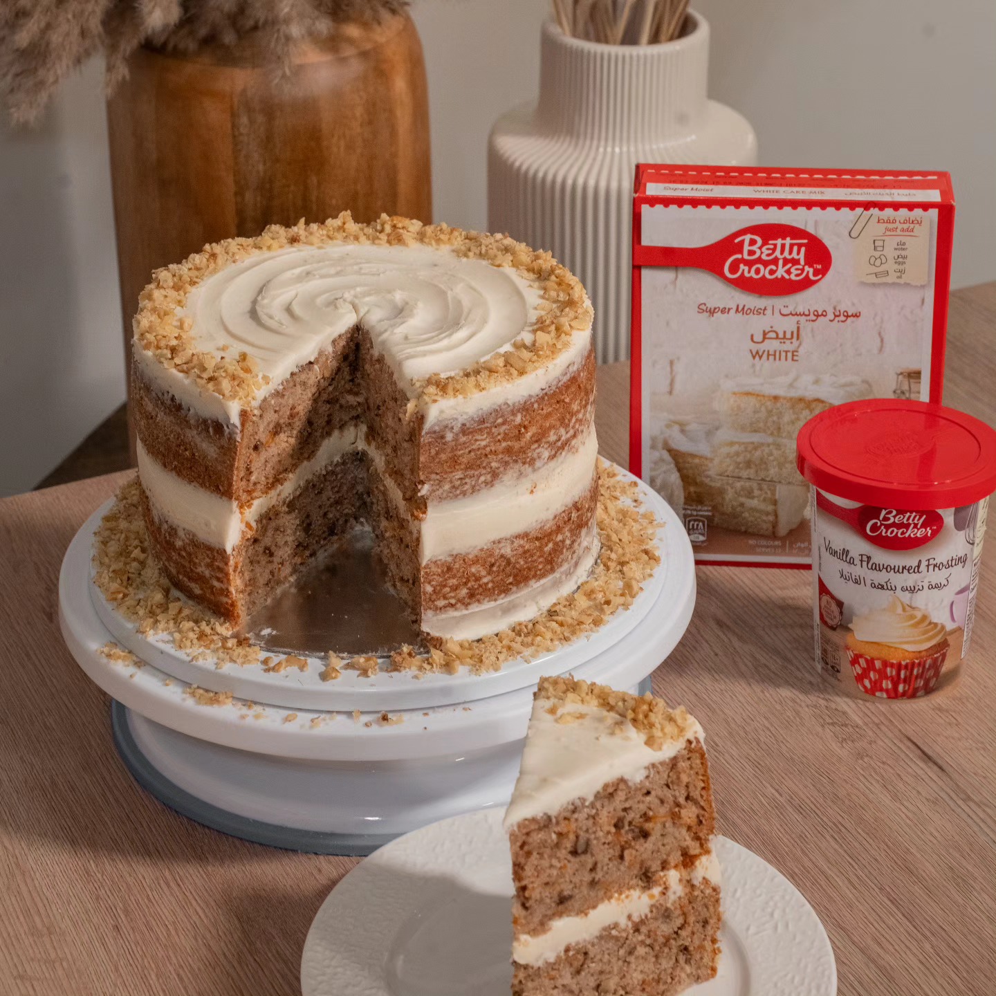 Layered walnut cake with vanilla frosting styled beside Betty Crocker cake mix and frosting